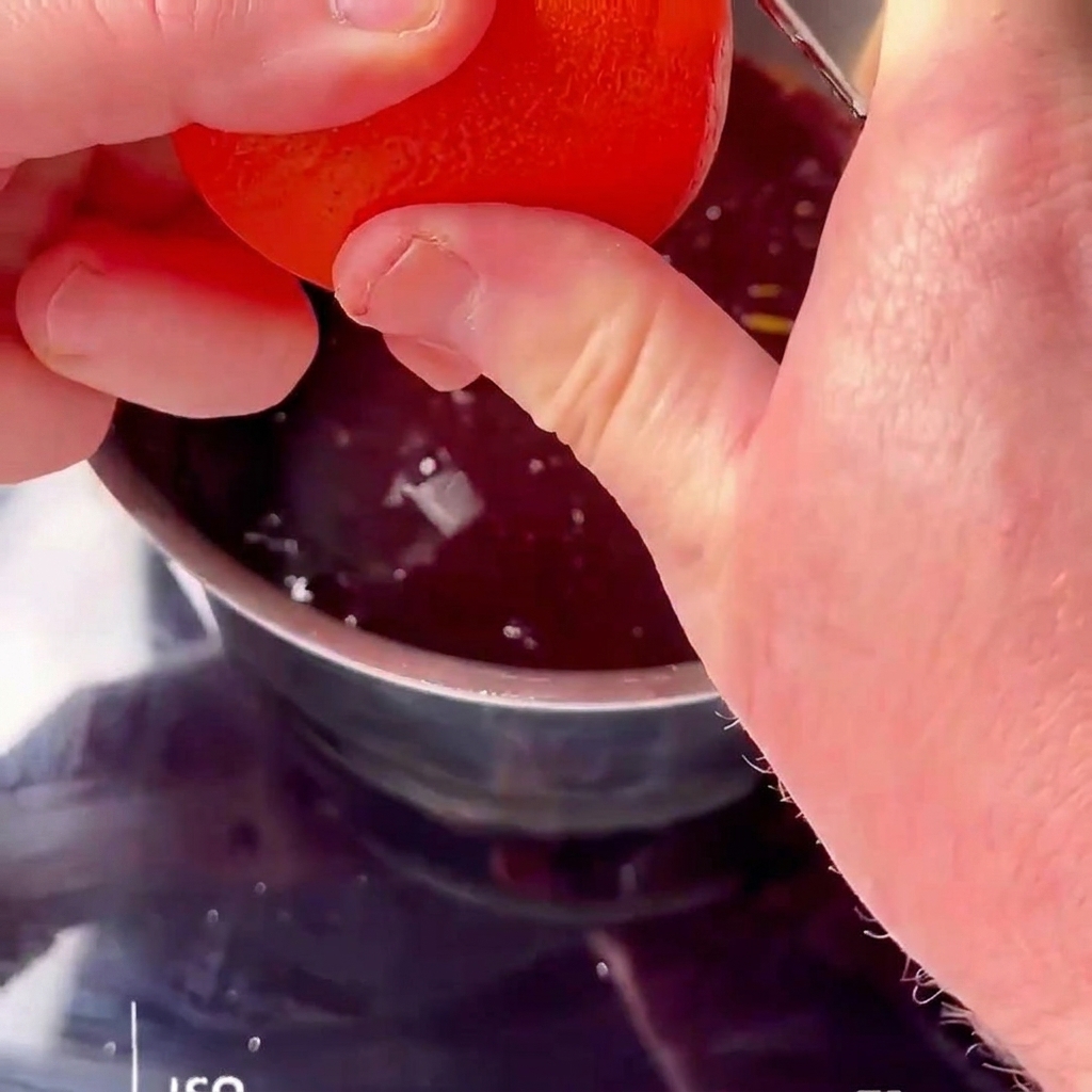 Frischer Orangensaft wird in eine köchelnde rote Kirschsauce gepresst.