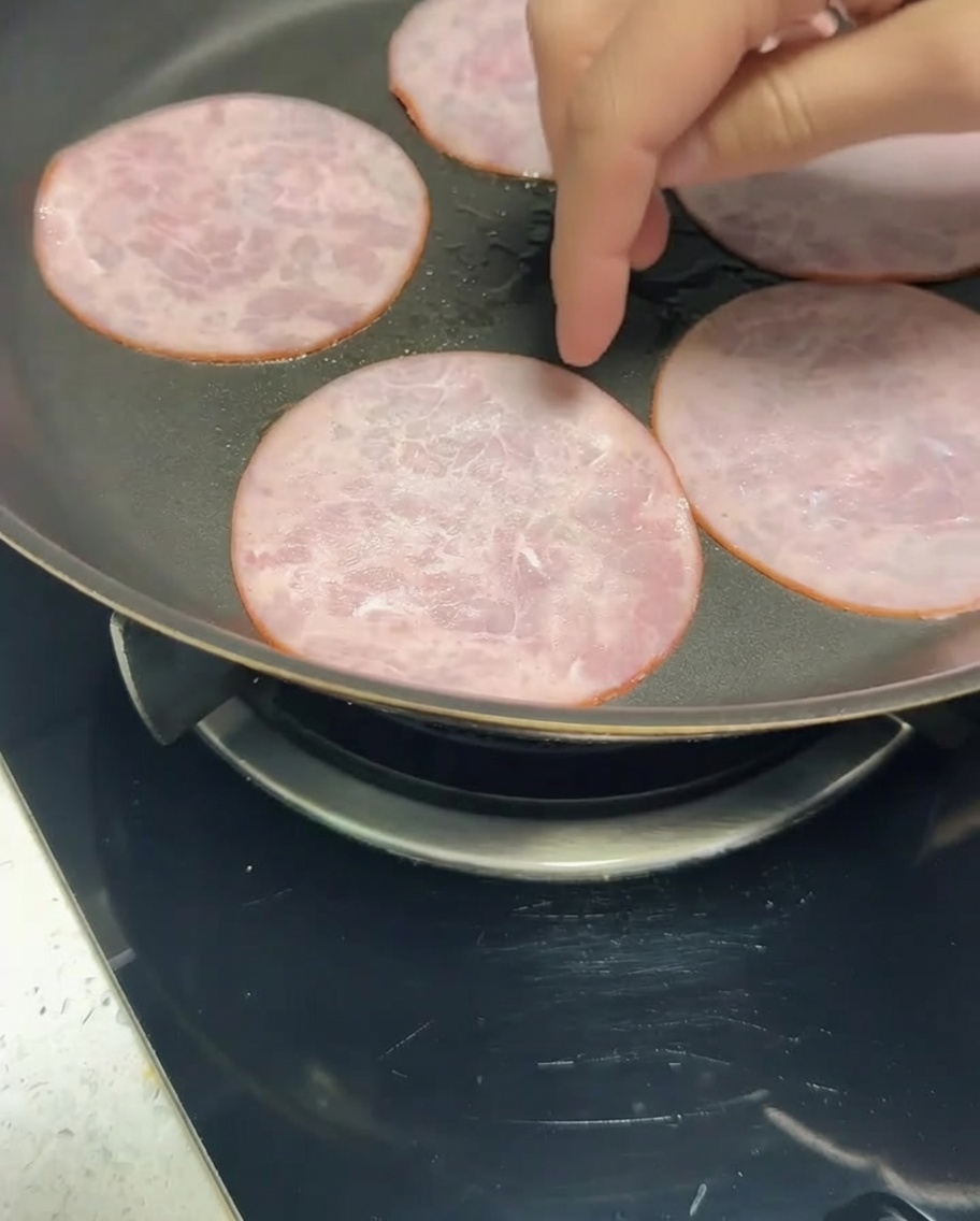 Fettreduzierter Speck brät in einer Pfanne, bis er gebräunt ist.