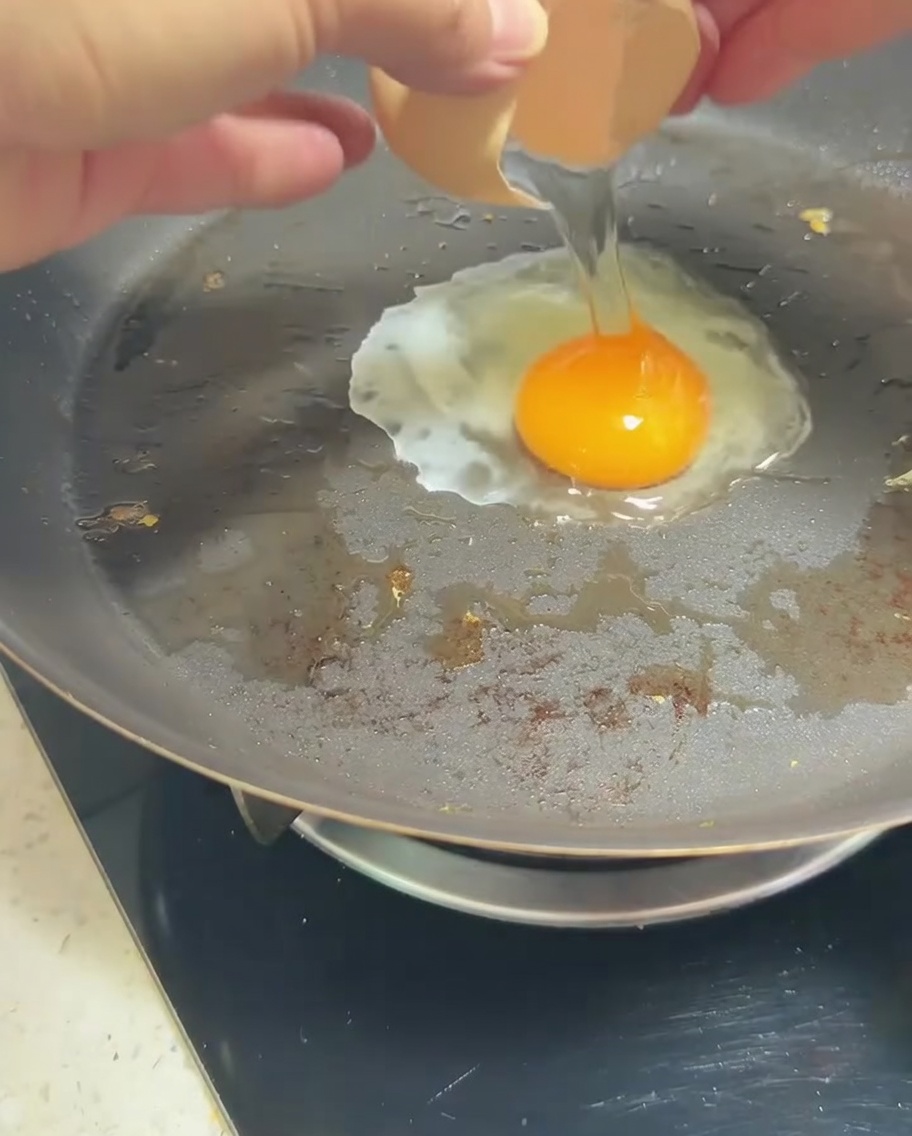 Ein einzelnes Ei in einer Pfanne mit einem goldgelben Eigelb.