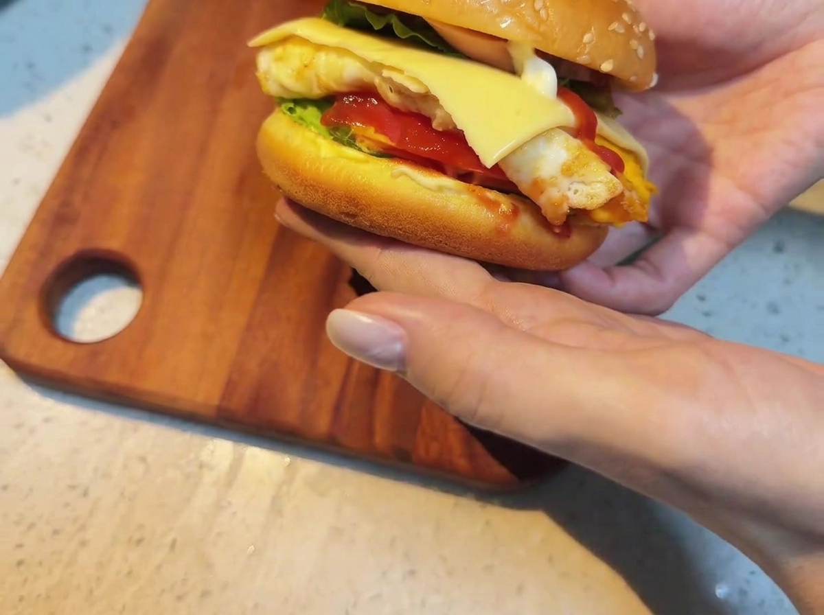 Eine Scheibe Käse wird auf den gestapelten Burger gelegt.