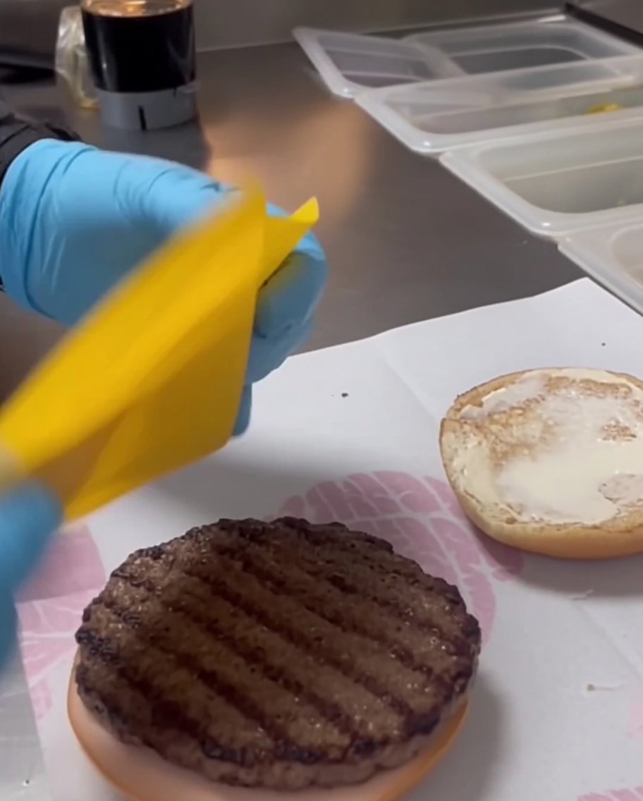Eine Scheibe Cheddar-Käse auf einem gegrillten Patty.
