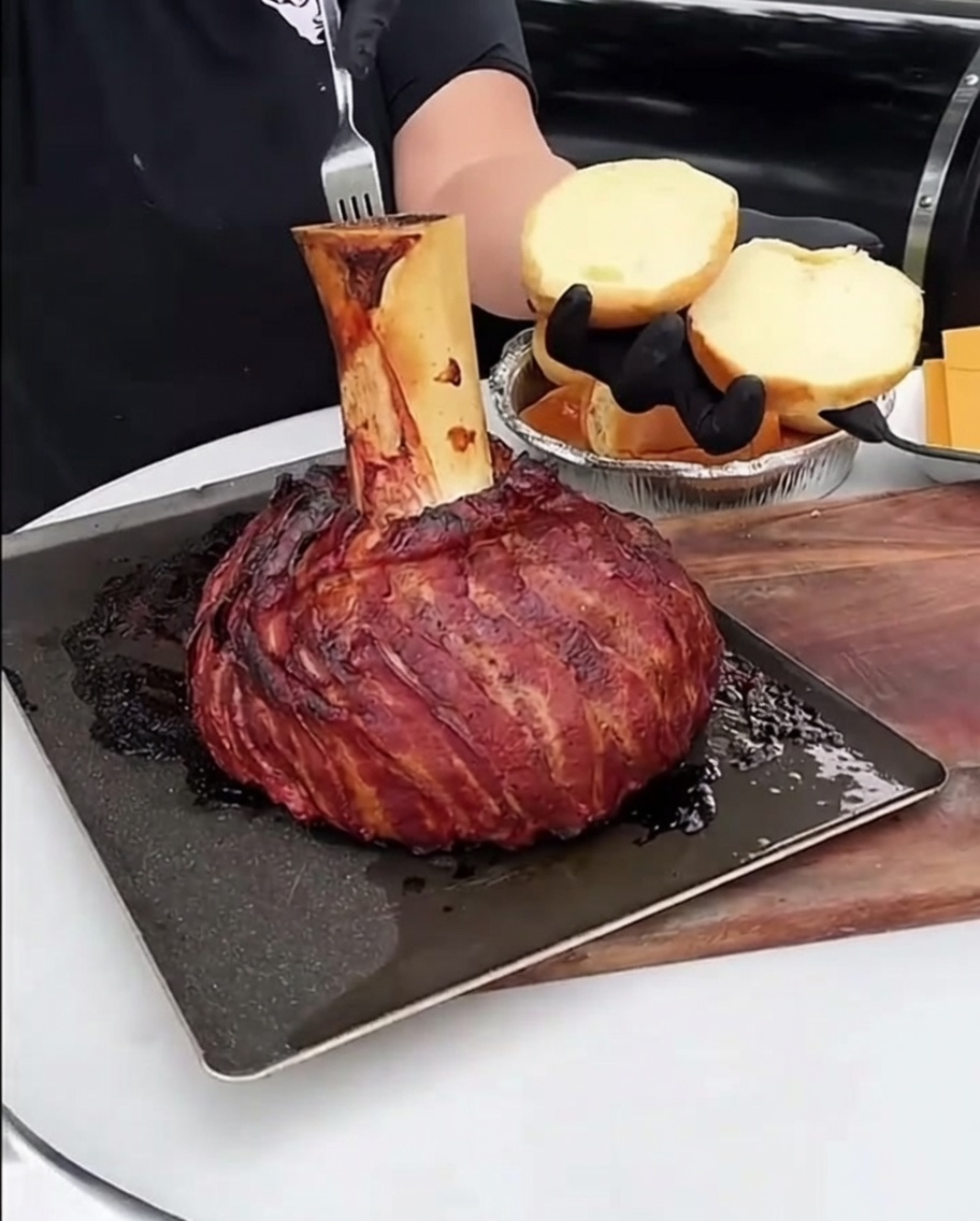 Ein Löffel voll mit reichhaltigem, geröstetem Knochenmark, das auf die Oberfläche eines gerösteten Burger-Brötchens gestrichen wird.