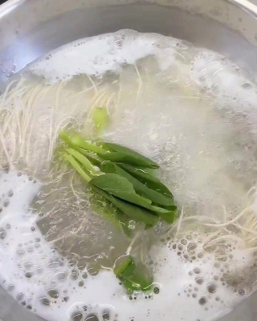 Frisches Blattgemüse wird in die kochende Suppe gegeben.