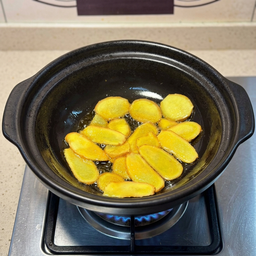 Goldbraune Ingwerscheiben braten in schimmerndem Sesamöl in einem Tontopf.