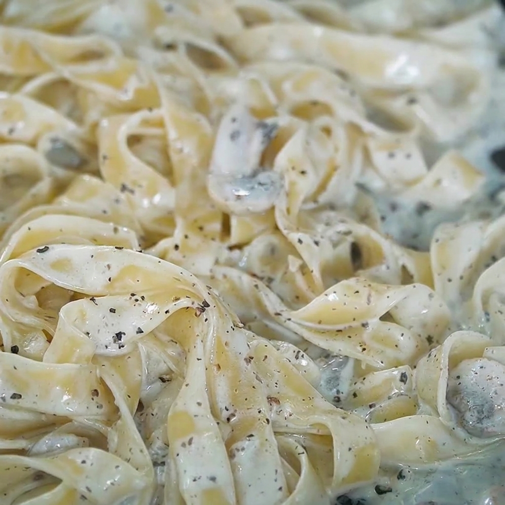 Salz und frisch gemahlener Pfeffer werden über die cremige Trüffel-Pasta gestreut.