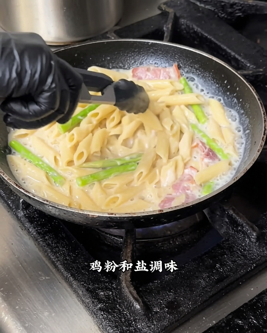 Penne-Nudeln werden mit weißer Sauce und schwarzem Trüffel in einer Pfanne bei mittlerer Hitze verrührt.
