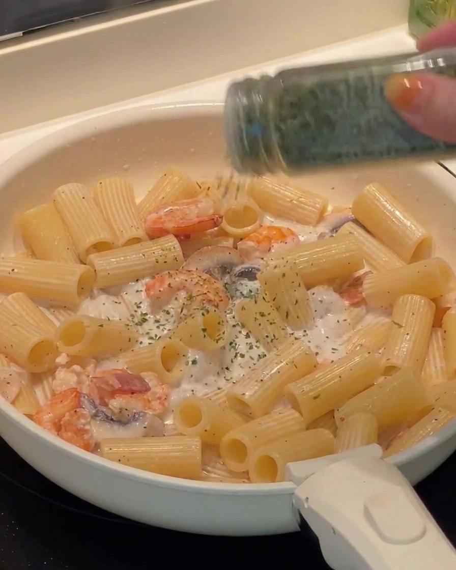 Frisch gehackte Petersilie wird über die fertige Pasta gestreut.