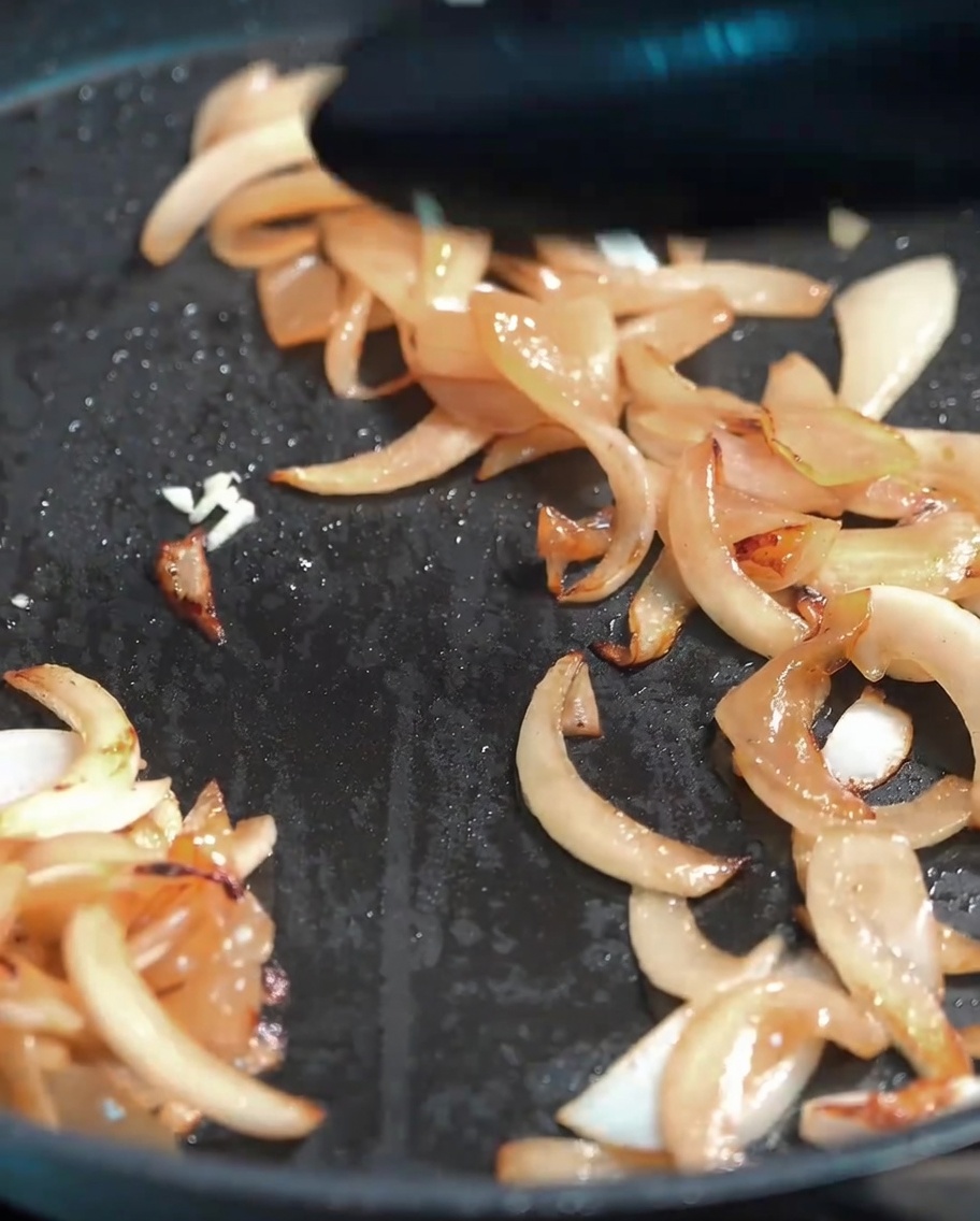 Frisch gehackter Knoblauch wird unter die weichen Zwiebeln gemischt.