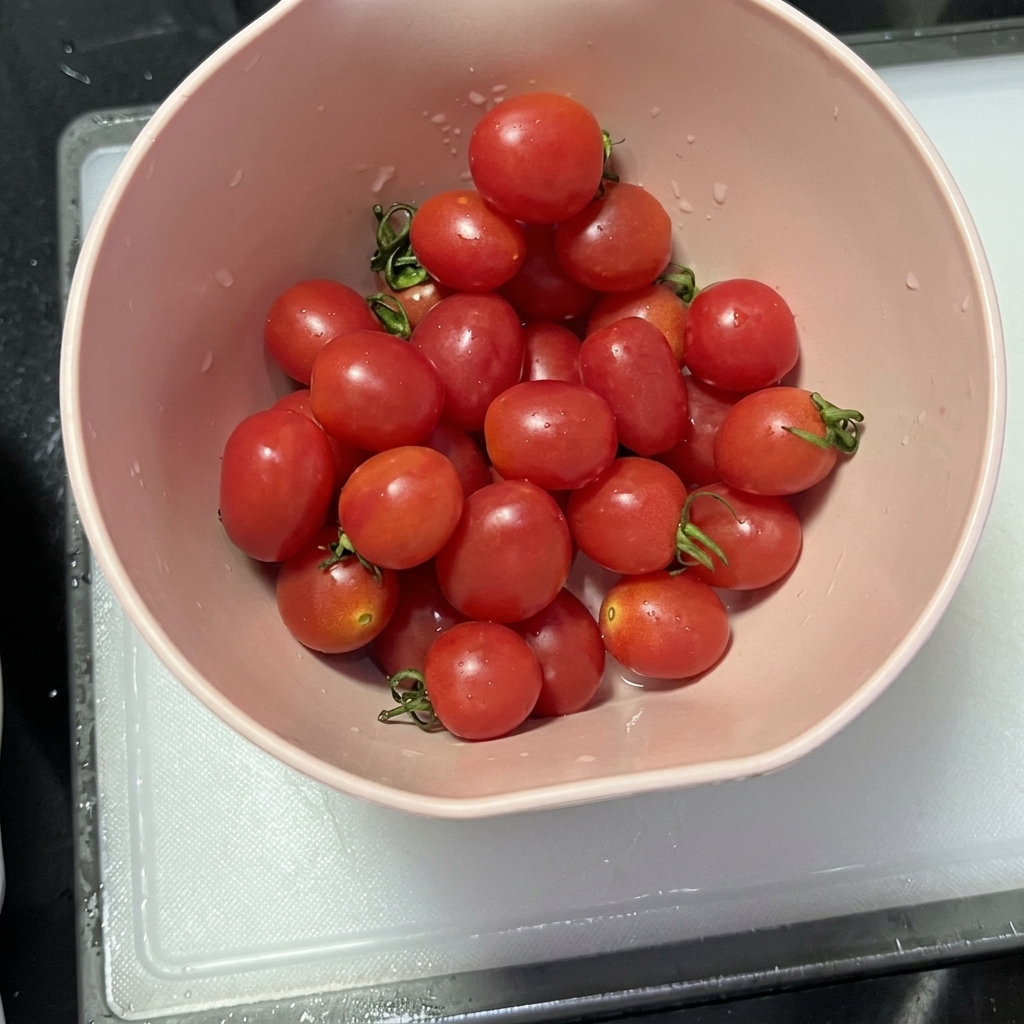 Halbierte Kirschtomaten liegen nach dem Schneiden auf einem sauberen Schneidebrett bereit.