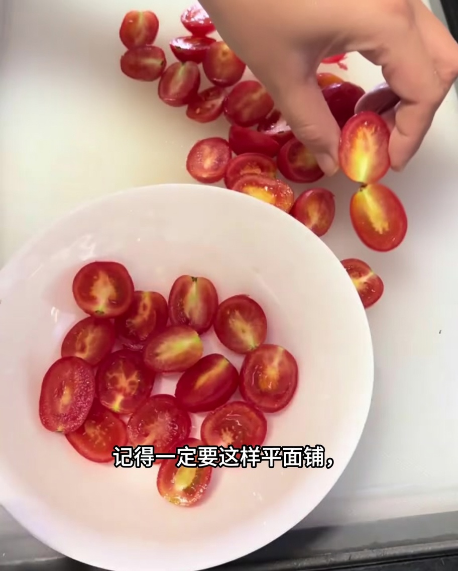 Nahaufnahme von halbierten Kirschtomaten, die ordentlich in einer einzigen Schicht in einer weißen Schüssel angerichtet sind.