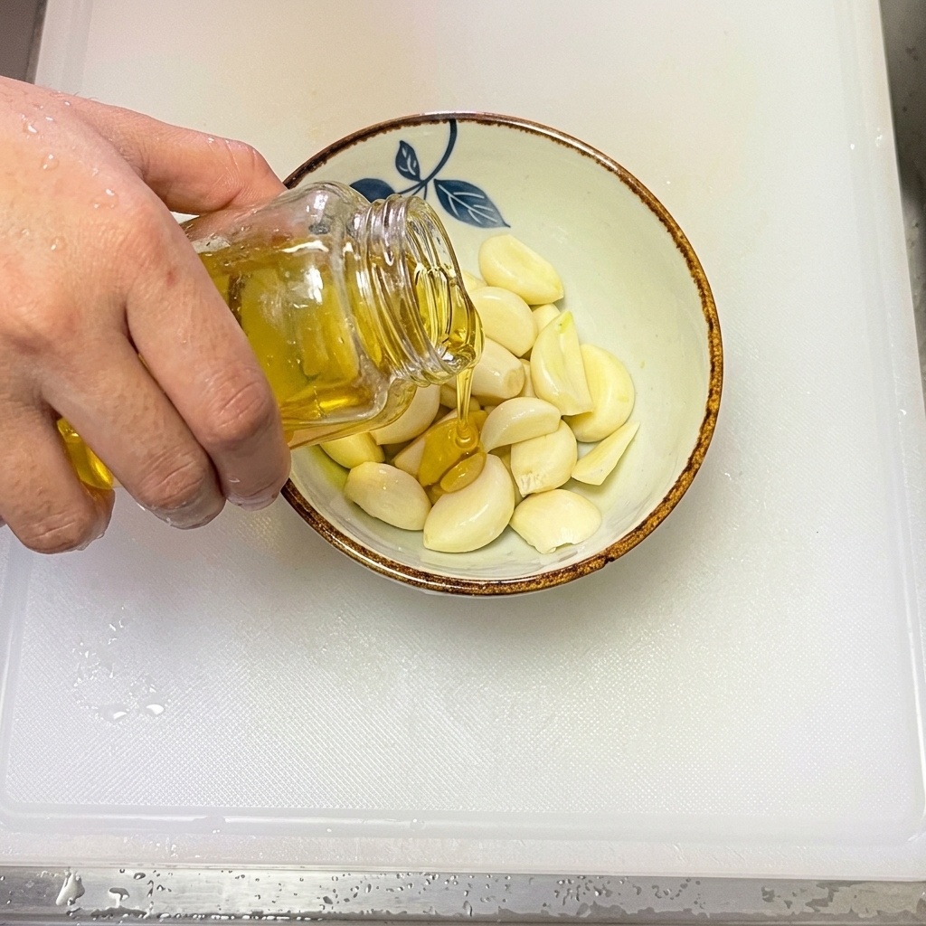 Olivenöl wird in eine Schüssel mit frischem, in dünne Scheiben geschnittenem Knoblauch gegossen.