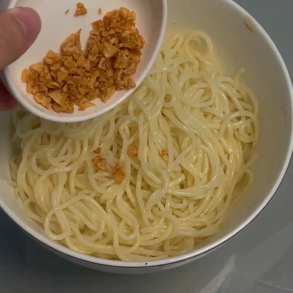 Knuspriger frittierter Knoblauch wird über die Nudelschüssel gestreut.