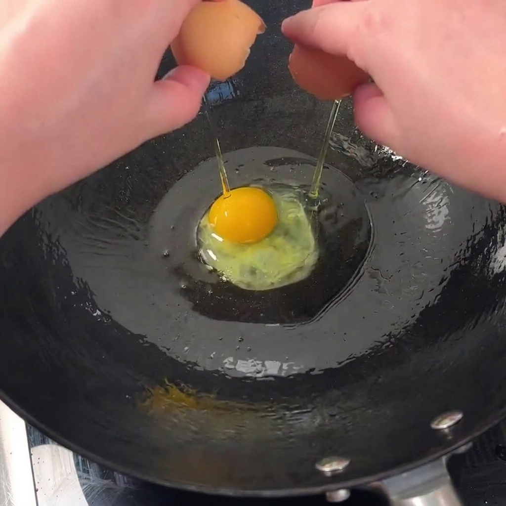 Zwei Eier brutzeln in einem heißen Wok, um knusprige Ränder zu bekommen.