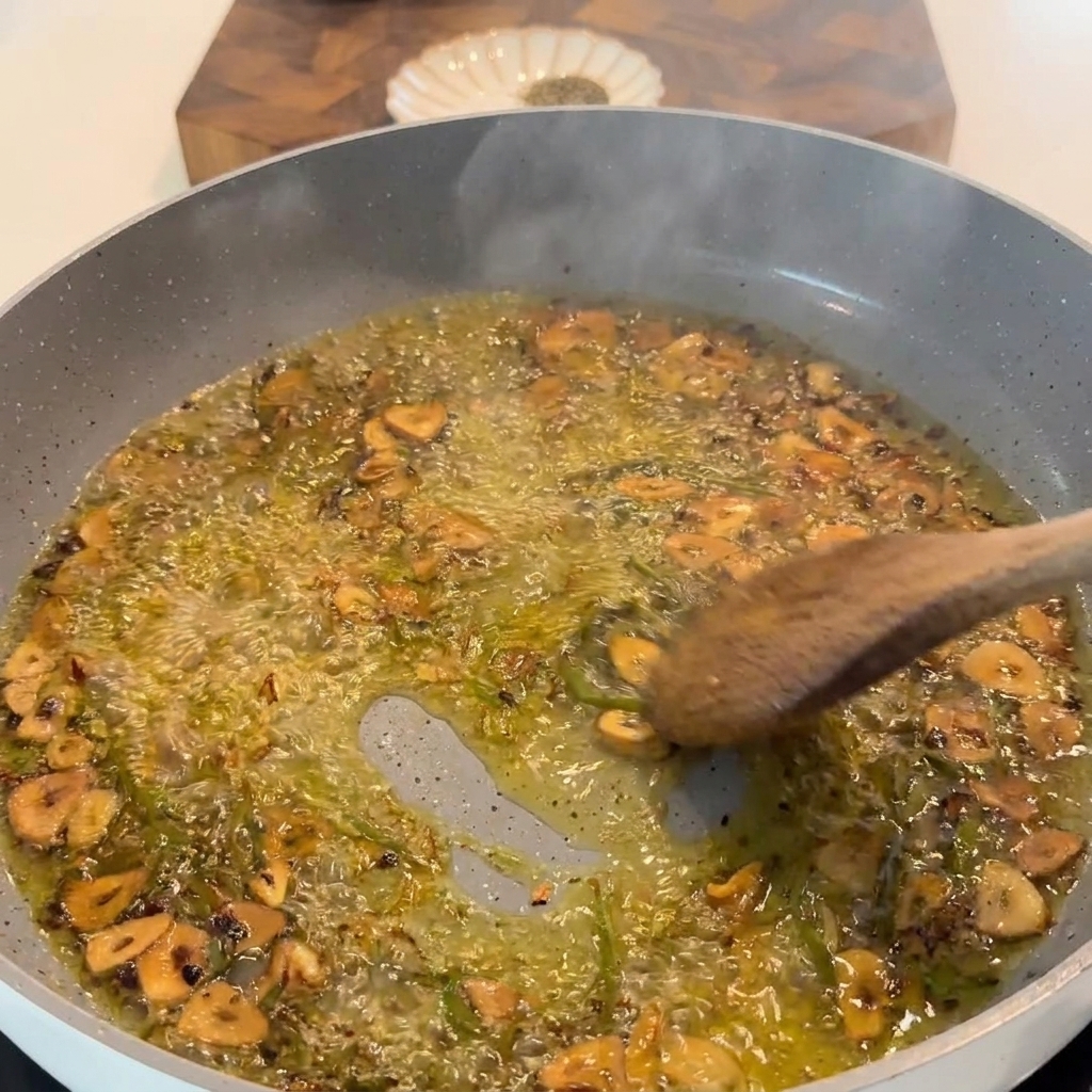 Frischer Zitronensaft wird in die Pfanne zu den schmorenden Knoblauch- und Kräuterzutaten gepresst.