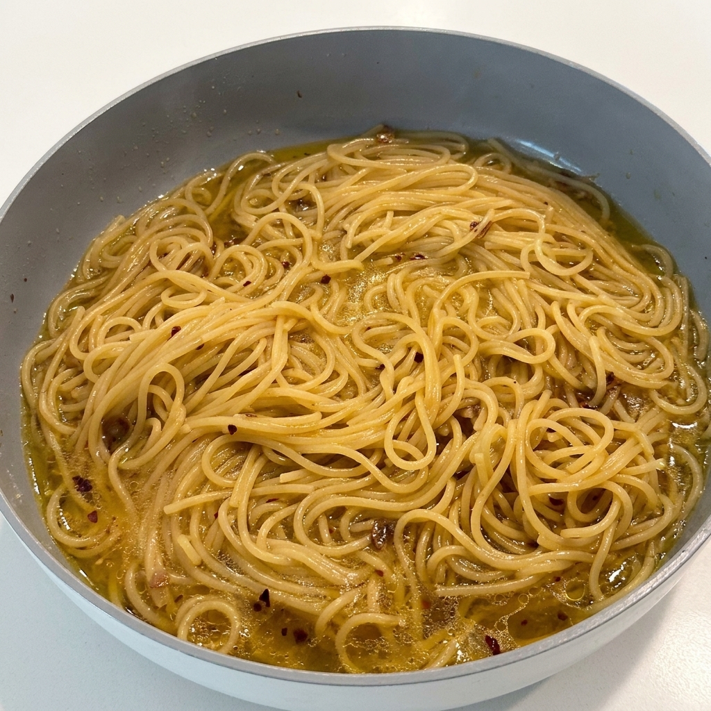 Die Pasta wird in der Pfanne mit schwarzem Pfeffer bestreut.