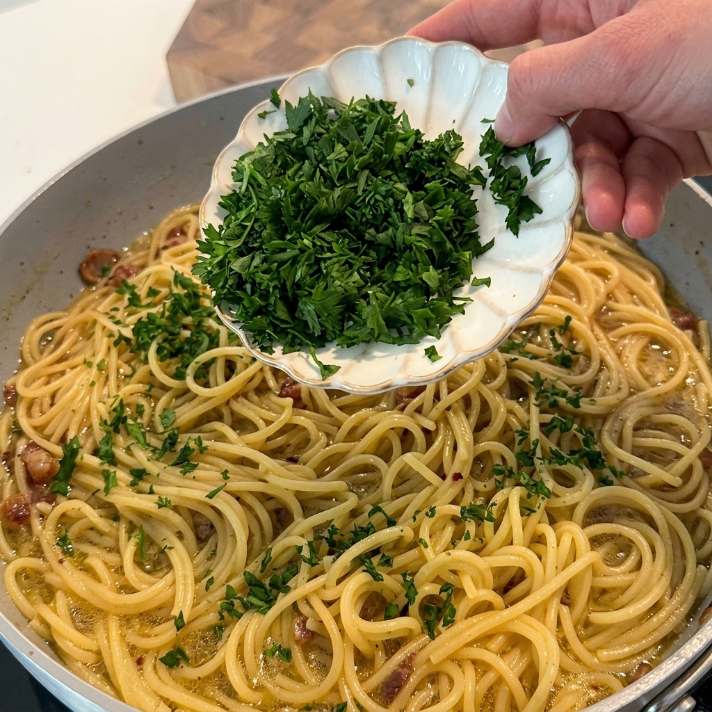 Gehackte frische Petersilie wird über die fertige Pasta in der Pfanne gestreut.