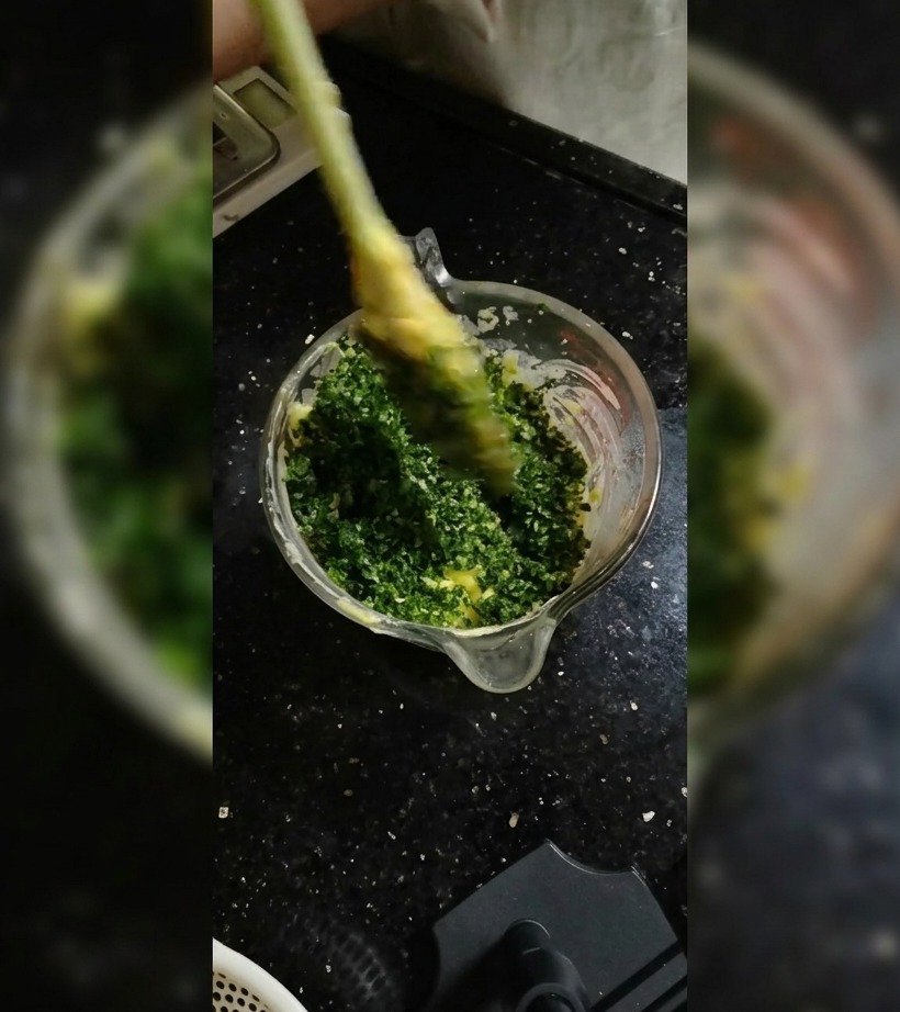 Ein Silikonspatel hebt Kräuter unter weiche Butter in einer Glasschüssel.