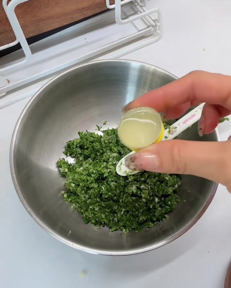 Zitronensaft wird in eine Metallschale mit der grünen Mischung gegeben.