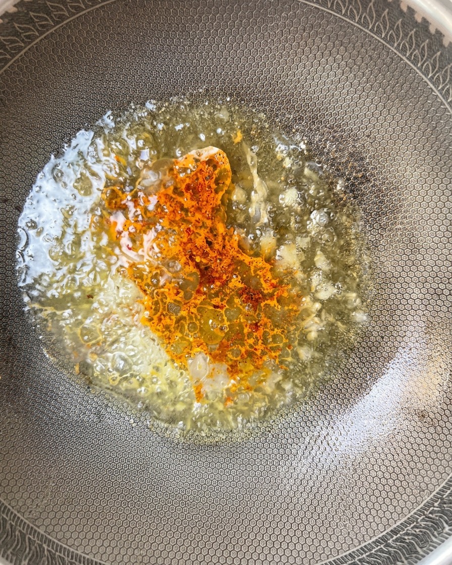 Chilipulver in der köchelnden Sauce.