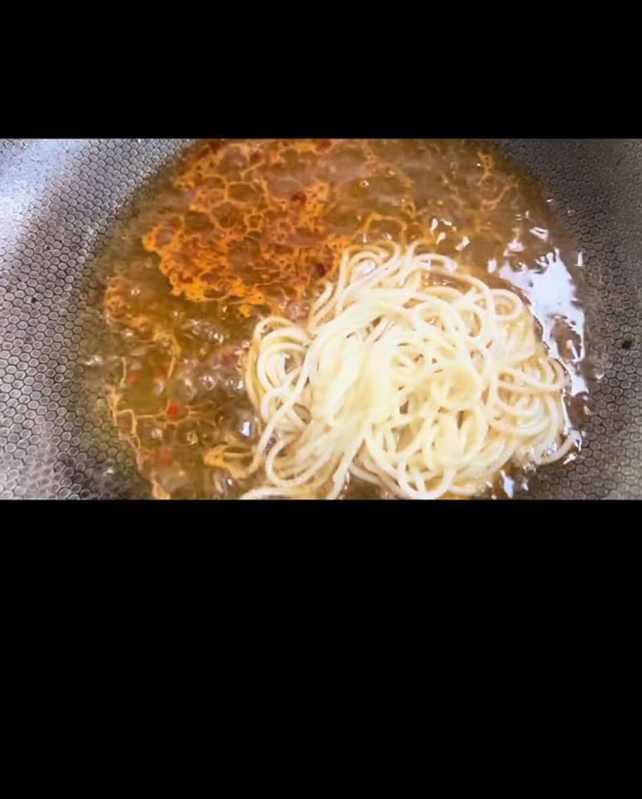 Gekochte Spaghetti werden in den Wok gegeben.