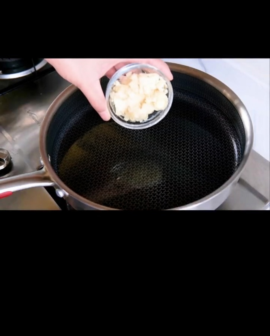 Geschnittener Knoblauch brät in schimmerndem Olivenöl in einer Pfanne.