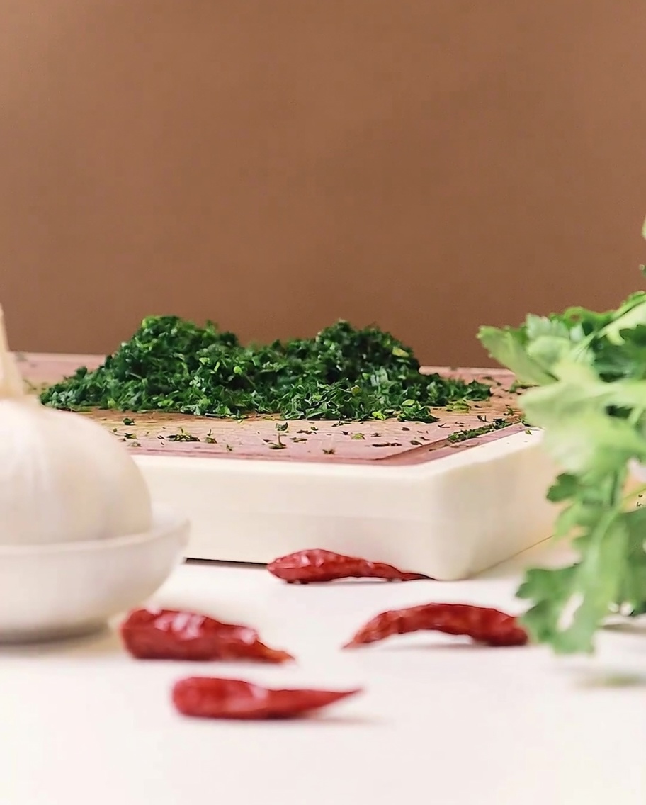 Dünne Scheiben von frischem Knoblauch auf einem Holzschneidebrett angerichtet.