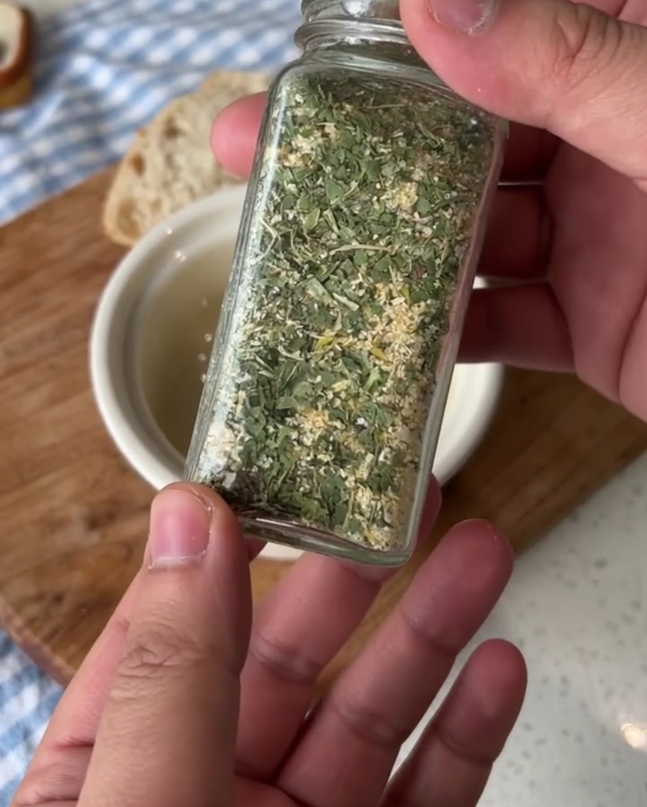 Eine kleine Keramikschale mit weicher Butter, die mit grünem Petersilien-Knoblauch-Salz gewürzt wird.