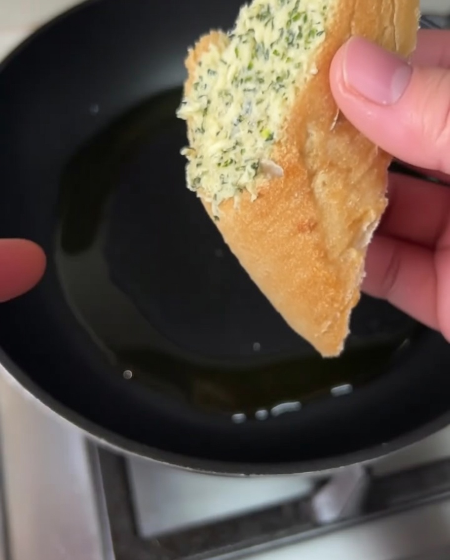 Mit Knoblauchbutter bestrichene Brotscheiben braten in der Pfanne im Olivenöl.