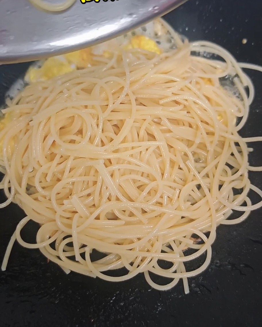 Blanchierter Brokkoli und halbierte Kirschtomaten werden in den Wok zu Spaghetti und Eiern gegeben.