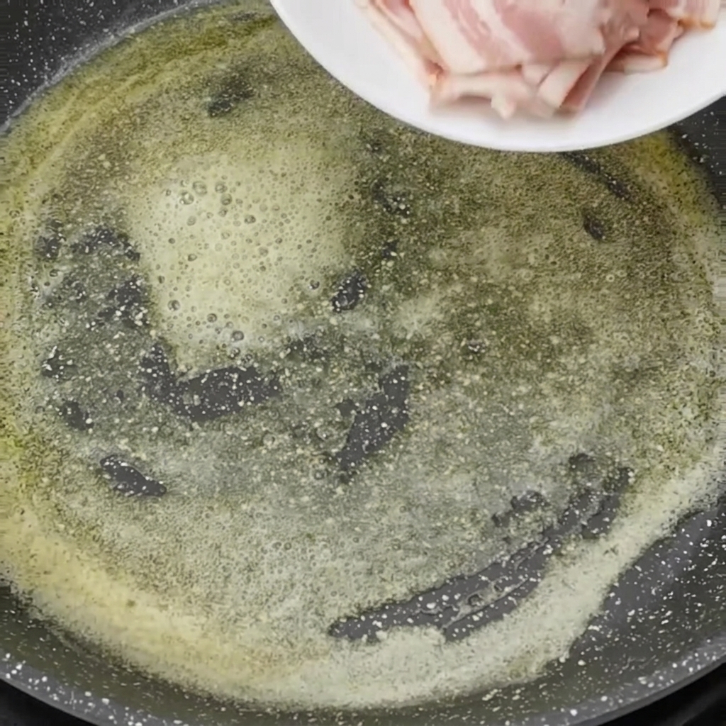 Rohe Speckwürfel werden in die heiße, geschmolzene Butter gegeben.