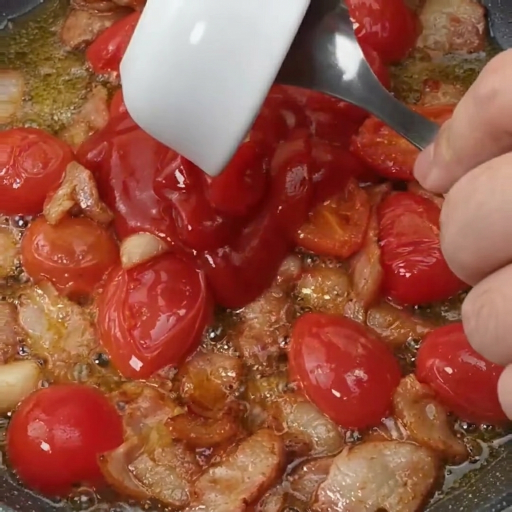 Tomatensauce und eine Prise Zucker werden zur Speck-Tomaten-Mischung gegeben.