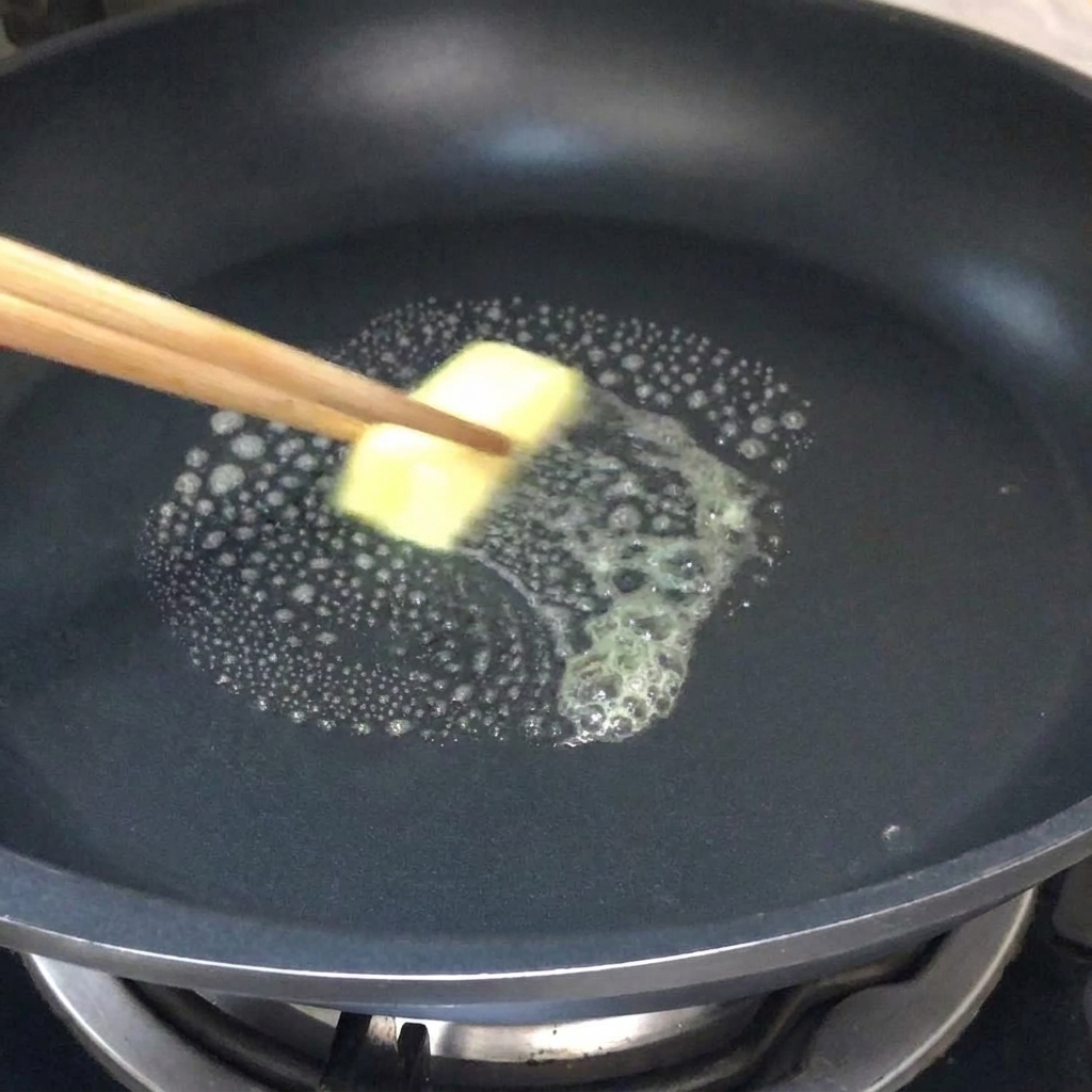 Ein Stück Butter schmilzt in einer heißen Pfanne.