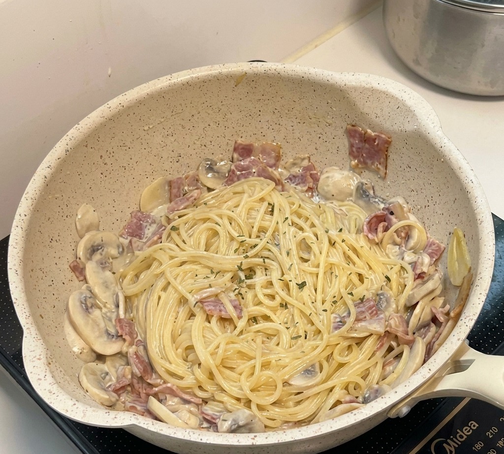Das fertige cremige Pilz-Pasta-Gericht in der Pfanne, garniert mit Kräutern.