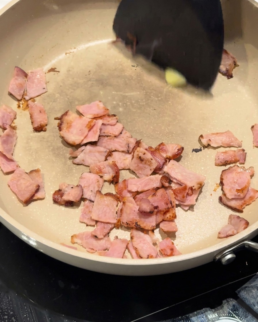 Gehackte weiße Zwiebeln werden in der Pfanne mit Speck und Butter verrührt.