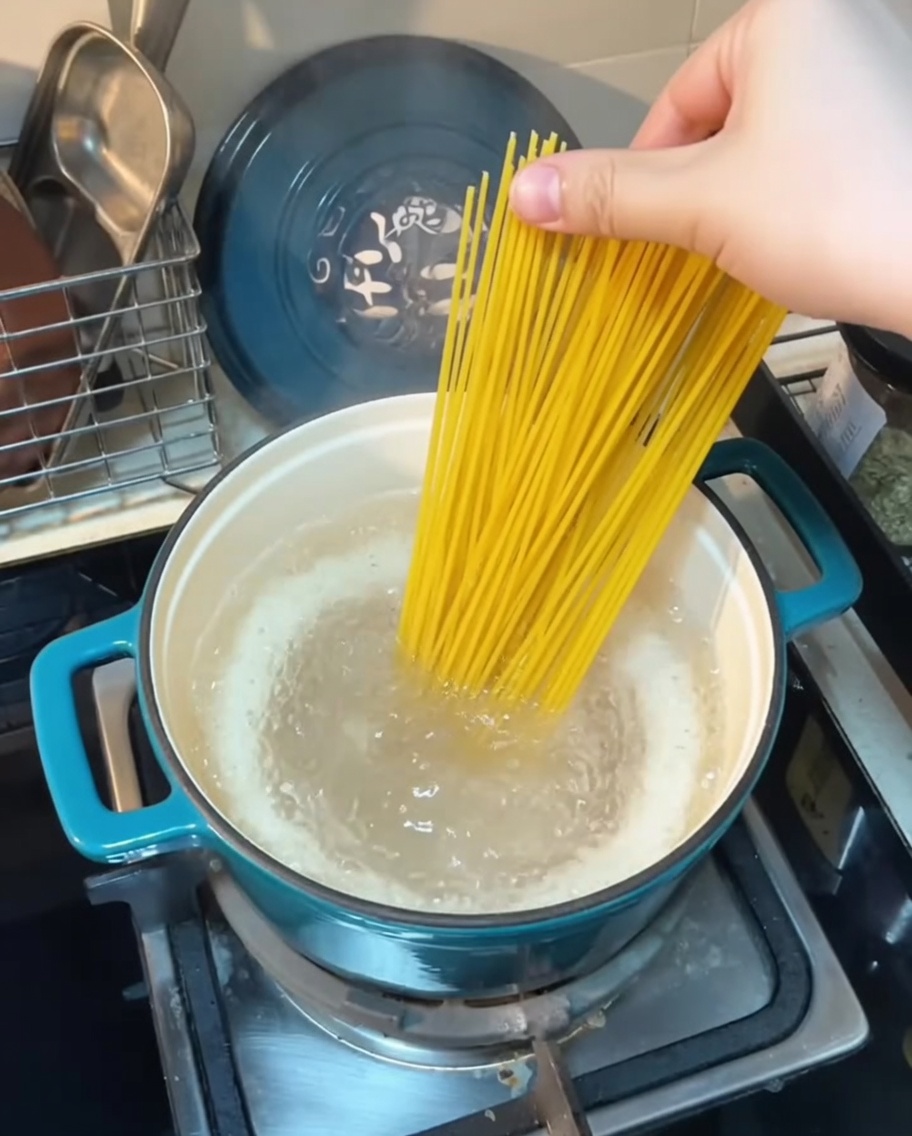 Spaghetti-Nudeln werden in einen Topf mit kochendem Wasser gegeben.