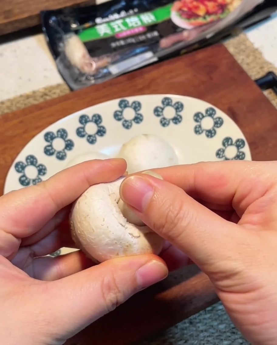 Dünn geschnittene weiße Champignons auf einem Holzschneidebrett.