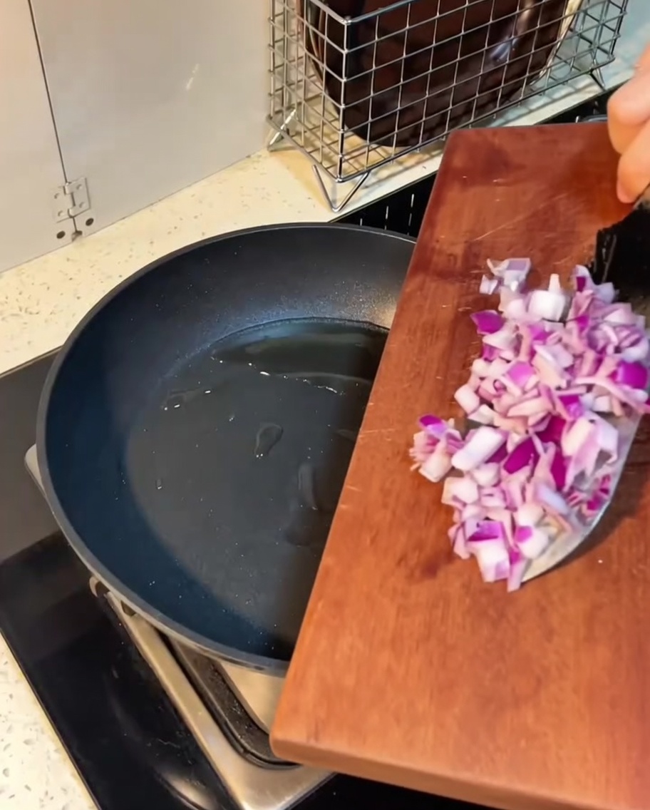 Gewürfelter Speck und Zwiebeln braten in geschmolzener Butter in einer Pfanne.