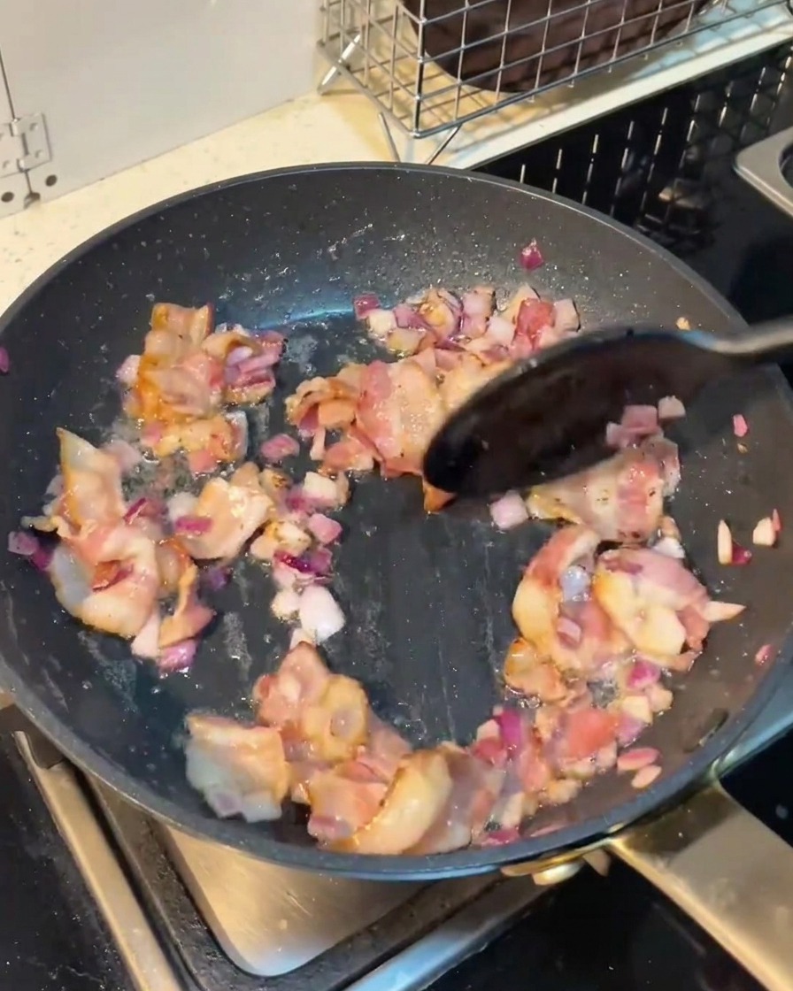 Geschnittene Pilze werden in der Pfanne mit Speck und Zwiebeln vermengt.