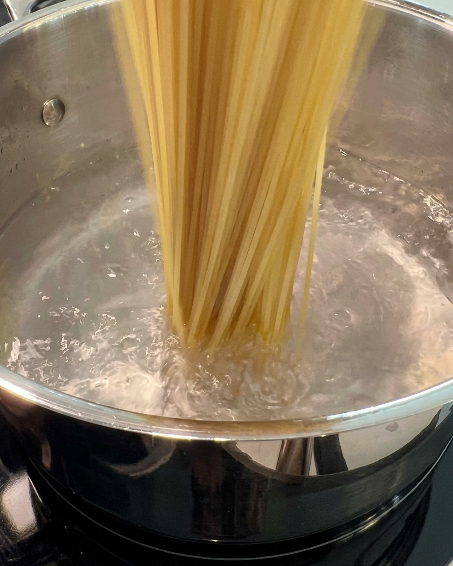Getrocknete Spaghetti-Nudeln werden in einen großen Topf mit kochendem Wasser gegeben.