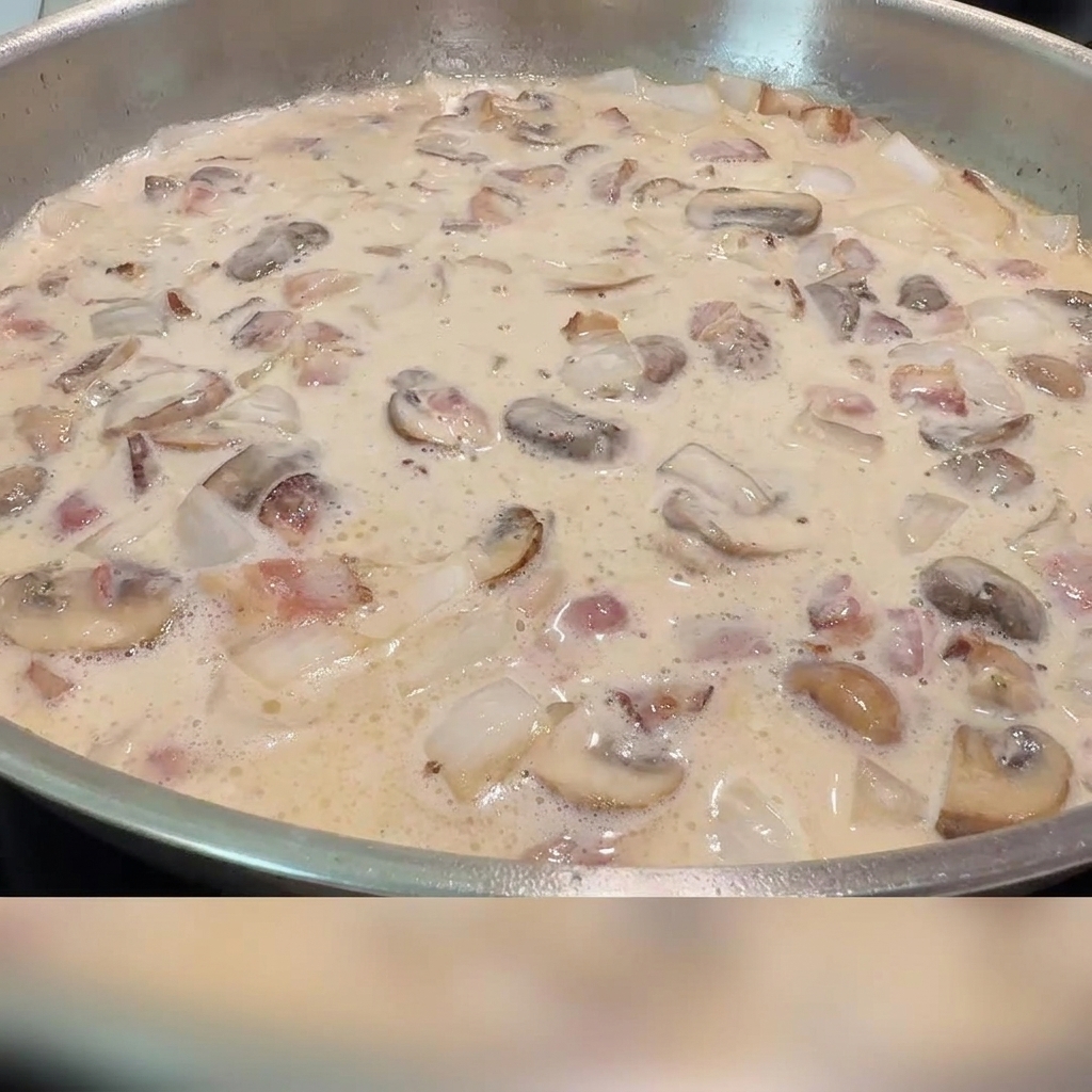 Salz und schwarzer Pfeffer werden in die cremige Speck-Pilz-Soße gestreut.