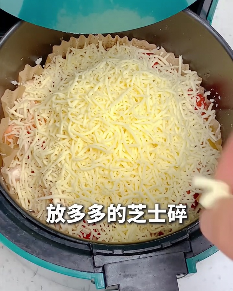 Geriebener Käse wird über die gesamte Pizza im Air Fryer gestreut.
