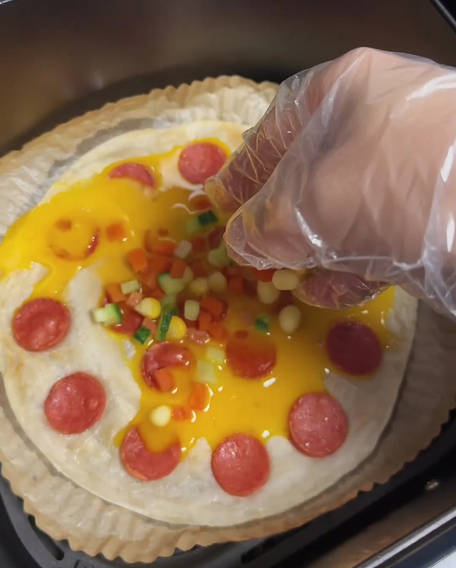 Ein Frühlingszwiebel-Pfannkuchen mit Ei, Wurst und bunt gehackten Karotten, Gurken und Maiskörnern.