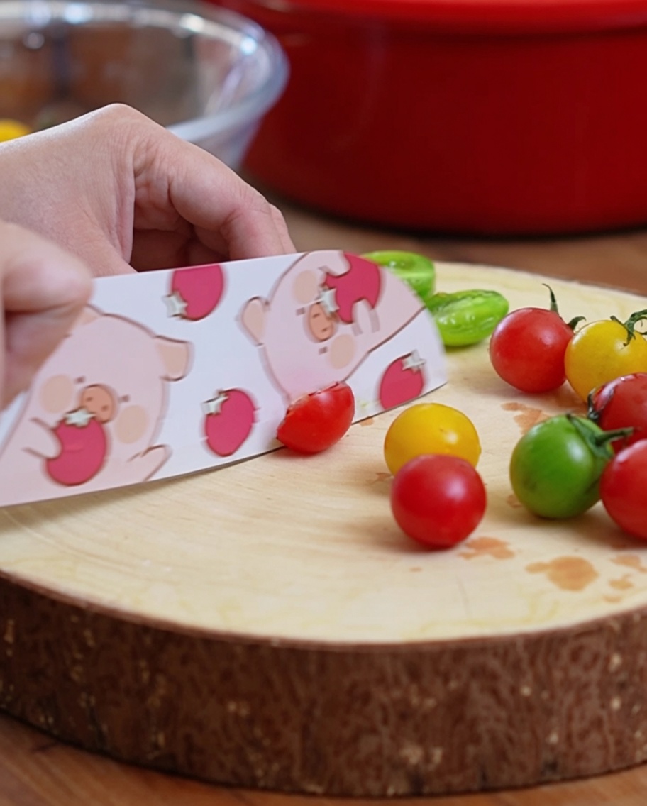 Kirschtomaten werden auf einem Schneidebrett halbiert.