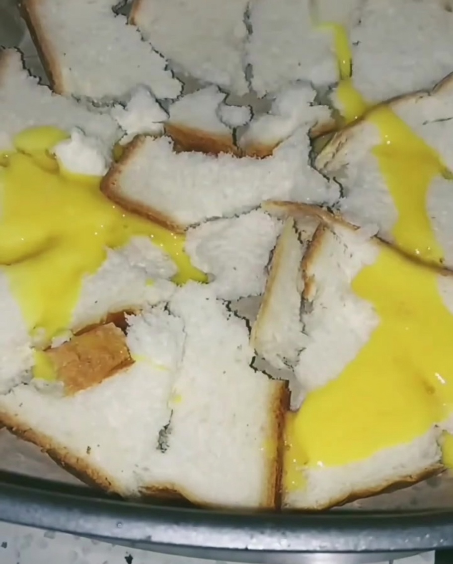 Verquirlte Eier werden über das Brot im Airfryer gegossen und bilden eine dünne gelbe Schicht.