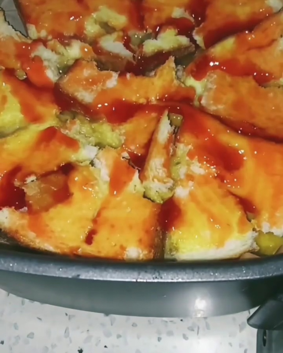 Buntes Gemüse wie Mais und Erbsen wird über die mit Tomatensoße bestrichene Basis gestreut.