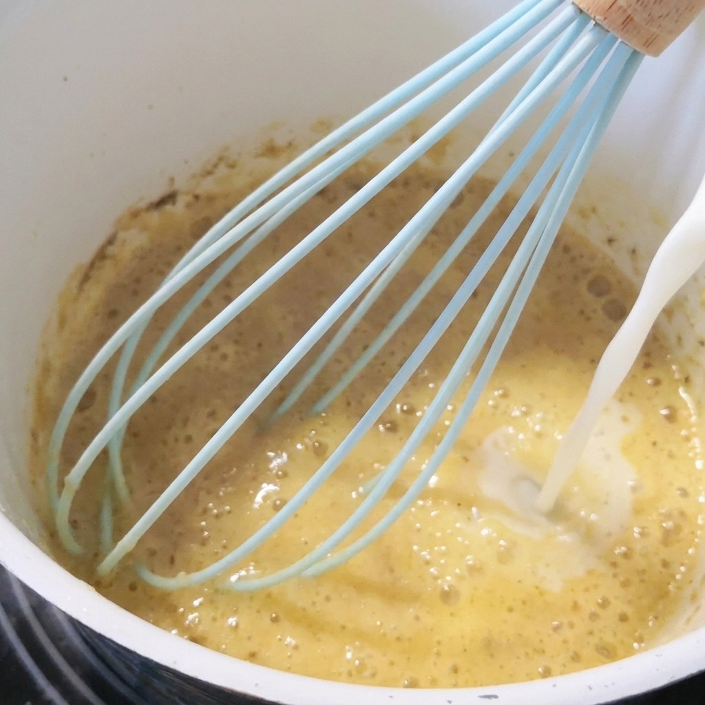 Milch wird unter ständigem Rühren in die Mehlschwitze gegossen.