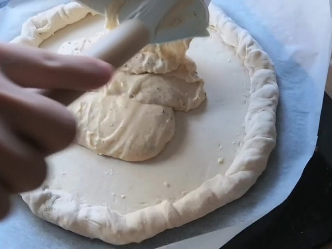 Peperoni- und Salami-Scheiben sind auf dem mit Sauce bestrichenen Pizzateig arrangiert.