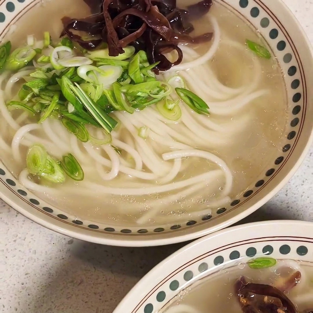 Eine fast fertige Schüssel Ramen, belegt mit Fleisch, Pilzen und Frühlingszwiebeln.