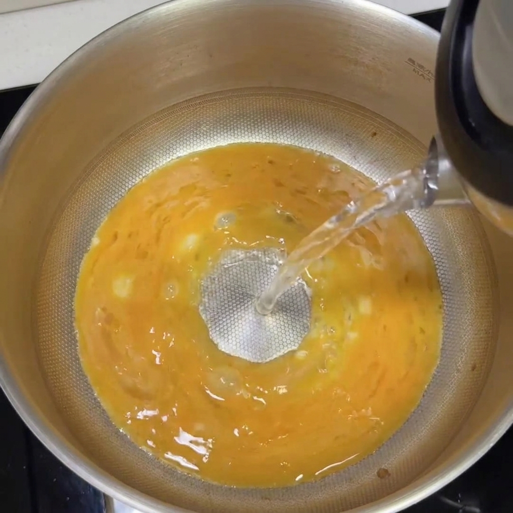 Kochendes Wasser wird in den Topf mit der Tonkotsu-Basis gegossen und verwandelt sich in eine cremige weiße Brühe.