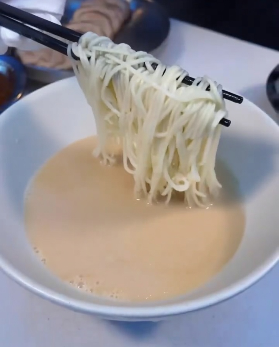 Dampfend heiße Ramen-Nudeln werden in eine Schüssel mit Suppe gegeben.